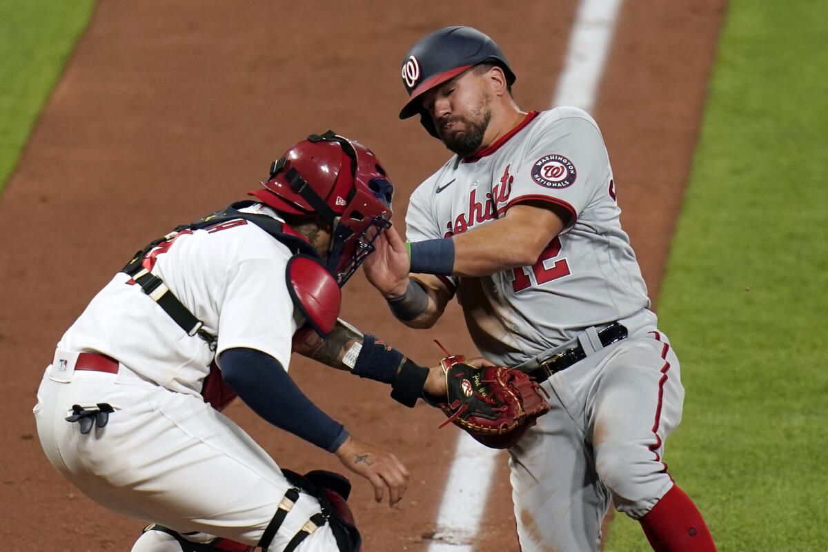 Washington Nationals' Kyle Schwarber, right, is tagged out at home by St. Louis Cardinals catcher Yadier Molina to end the top of the eighth inning of a baseball game Monday, April 12, 2021, in St. Louis. (AP Photo/Jeff Roberson)