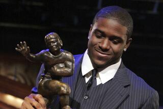 USC tailback Reggie Bush picks up the Heisman Trophy after winning the award on Dec. 10, 2005