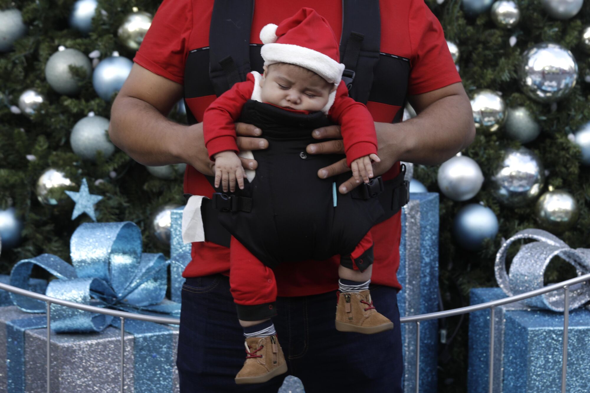 Jesse Aguilar, 2 months old, sleeps while strapped to his father, Jesus Aguilar.