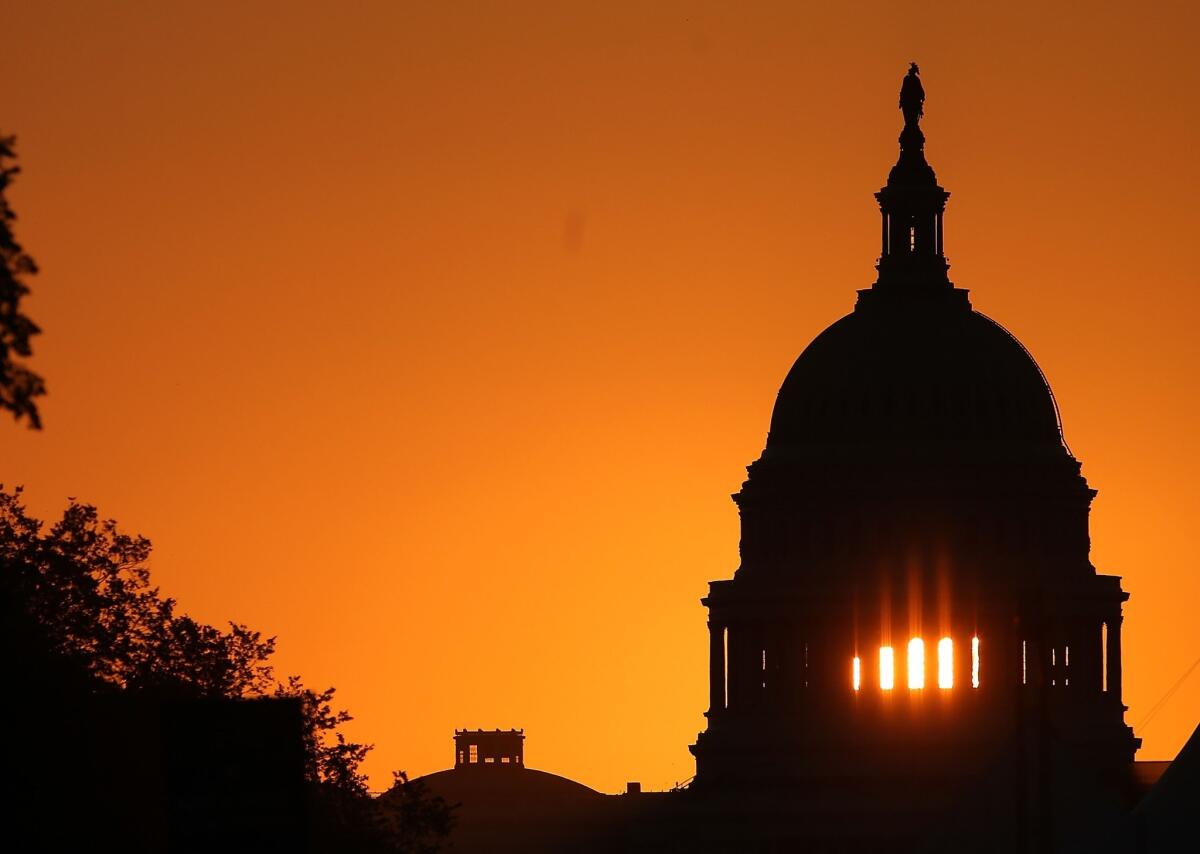 The early morning sun rises behind the Capitol in Washington.