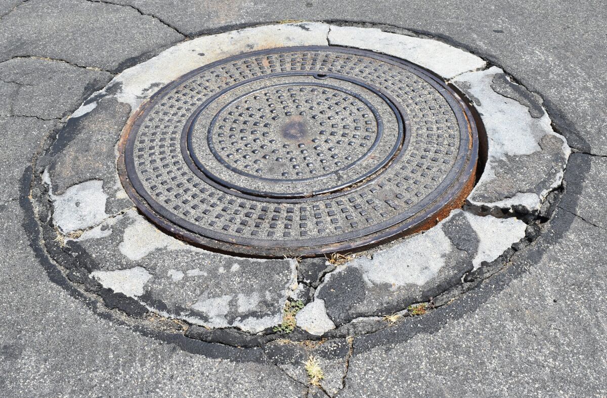 One of several manholes on Azucar Way, with a large space between the hole cover and surrounding concrete.