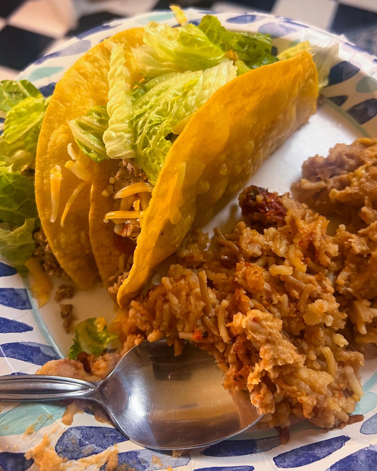 A plate with two tacos, Mexican rice and refried beans