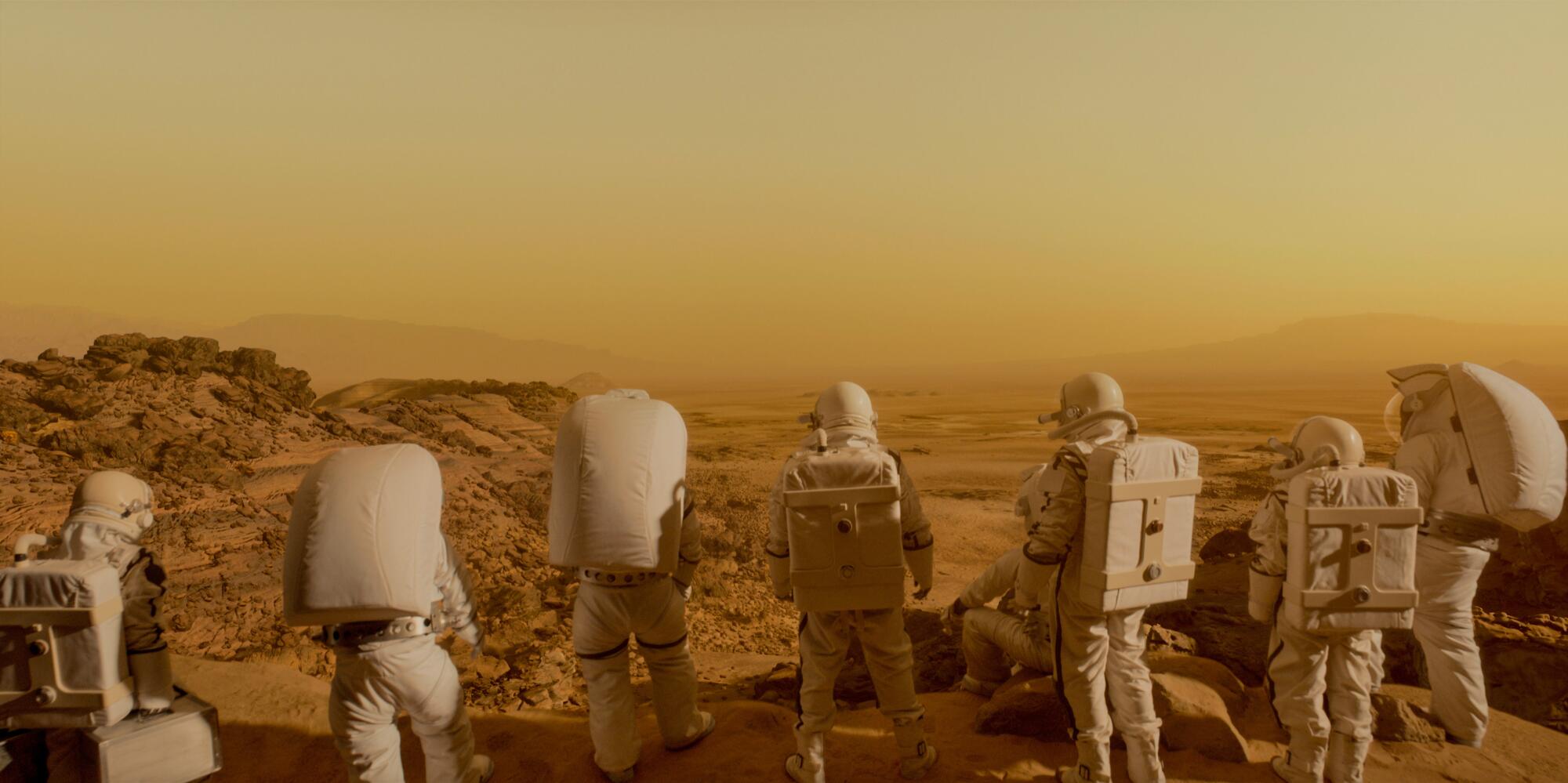 A line of astronauts walking through a Mars landscape