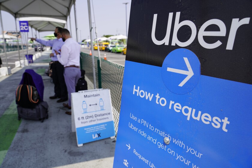 FILE - Travelers request an Uber ride at Los Angeles International Airport's LAX-it pick up terminal on Aug. 20, 2020. Uber’s ride-hailing service edged closer to returning to its pre-pandemic levels during the final three months of last year. But prospects for the San Francisco-based company remain clouded by the future direction of the novel coronavirus that has plagued its business. (AP Photo/Damian Dovarganes, File)