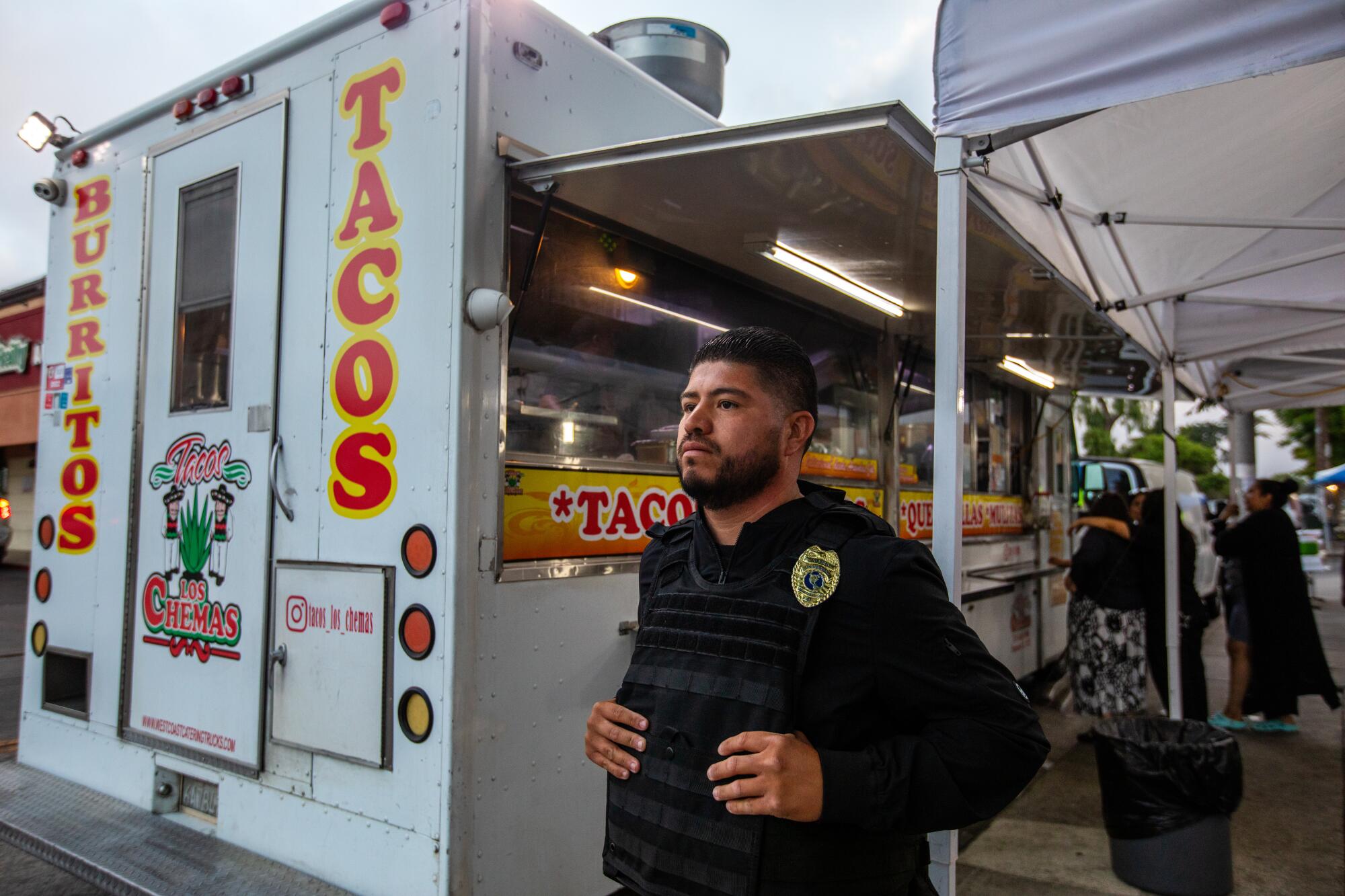 Security guard Fernando Gonzalez stands outside a taco truck