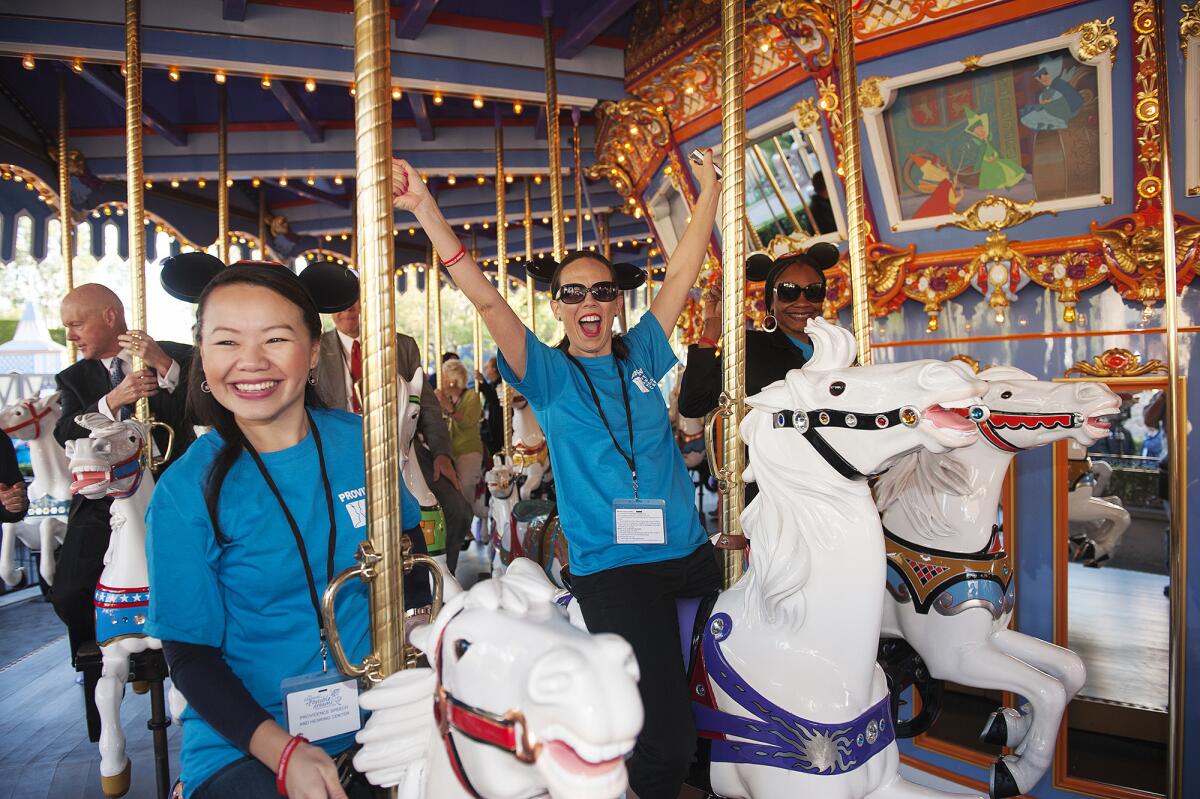 Anza Vang, left, Pamela Sailor, center, and Dientre Leon with the Providence Speech and Hearing Center ride the King Arthur Carrousel at Disneyland.