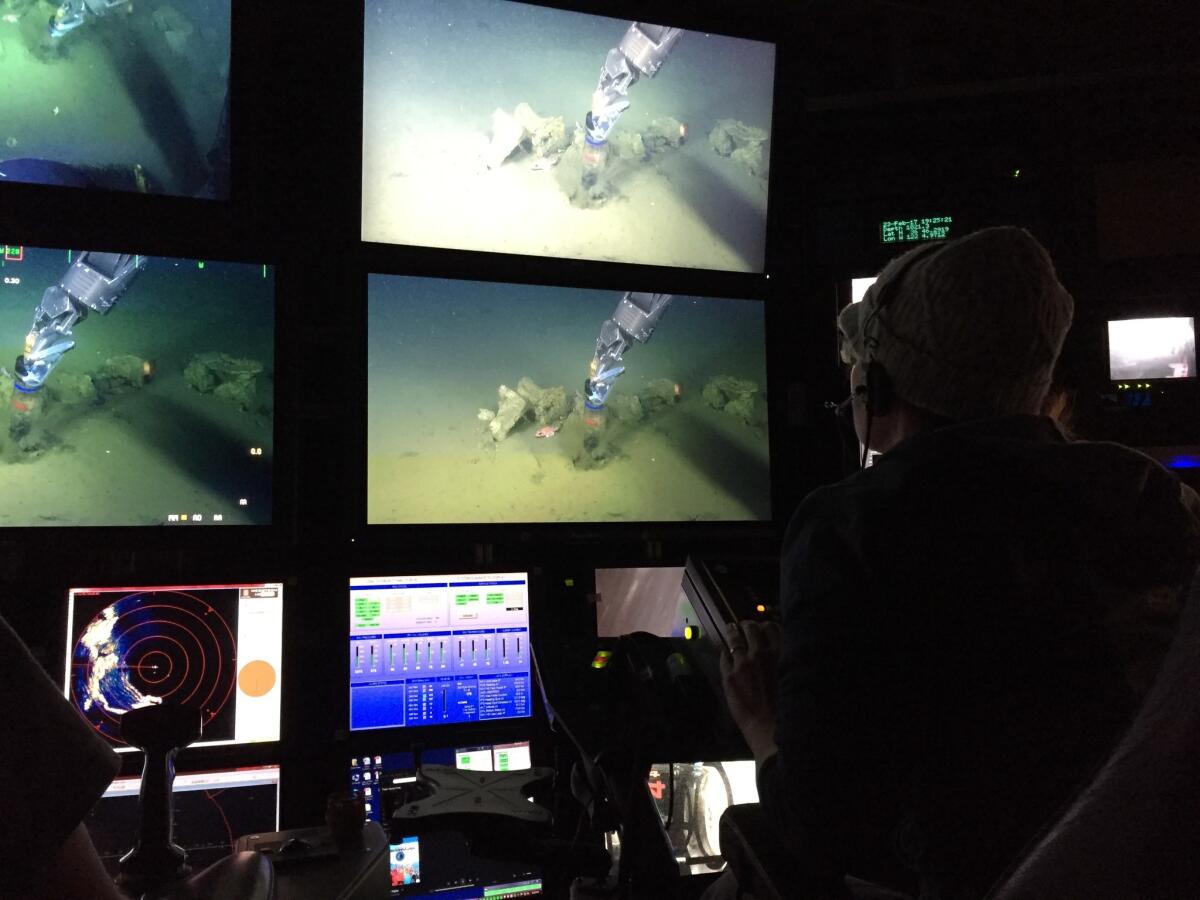 Caltech geobiologist Victoria Orphan watches as the pilots use the rover's robotic arm to press a sediment sampler into the ocean floor.