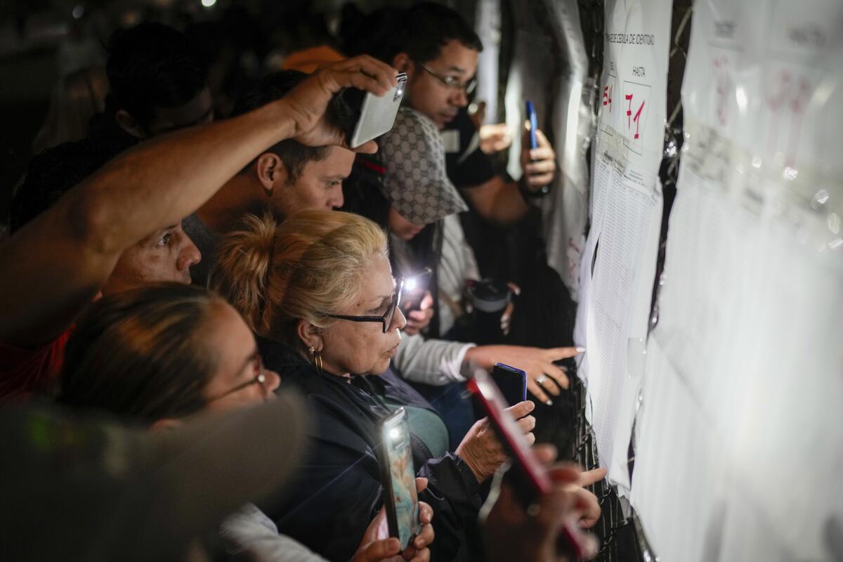 Voters look at electoral lists before the opening of the polls for presidential elections in Caracas.