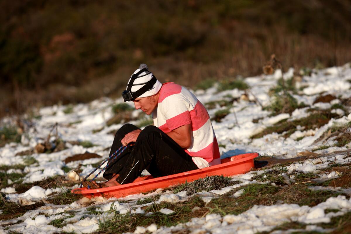 Ryan Schulenburg, 19, of Foothill Ranch goes sledding in his beach sandals after a rare snowfall gathered on a hillside in Robinson Ranch on Wednesday.