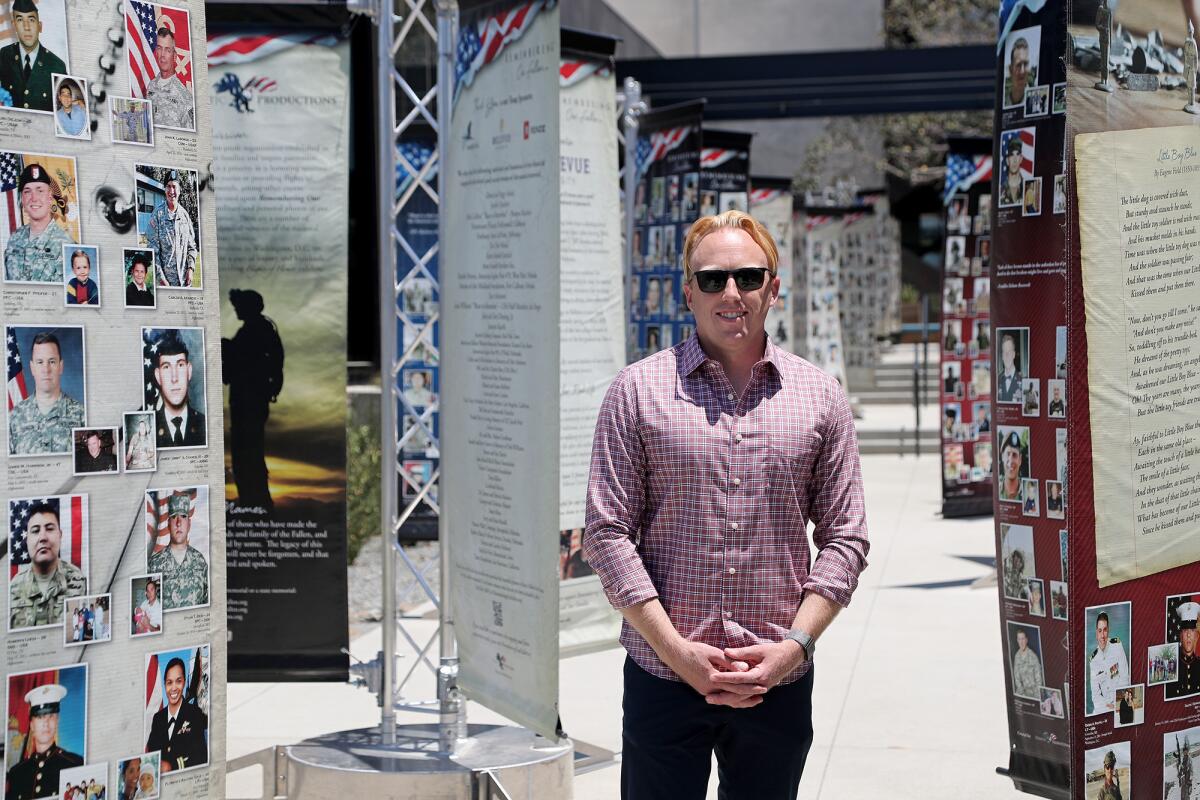 Tom Williams, operations lead for Anduril, poses Wednesday in front of a traveling photo exhibition created by his parents. 
