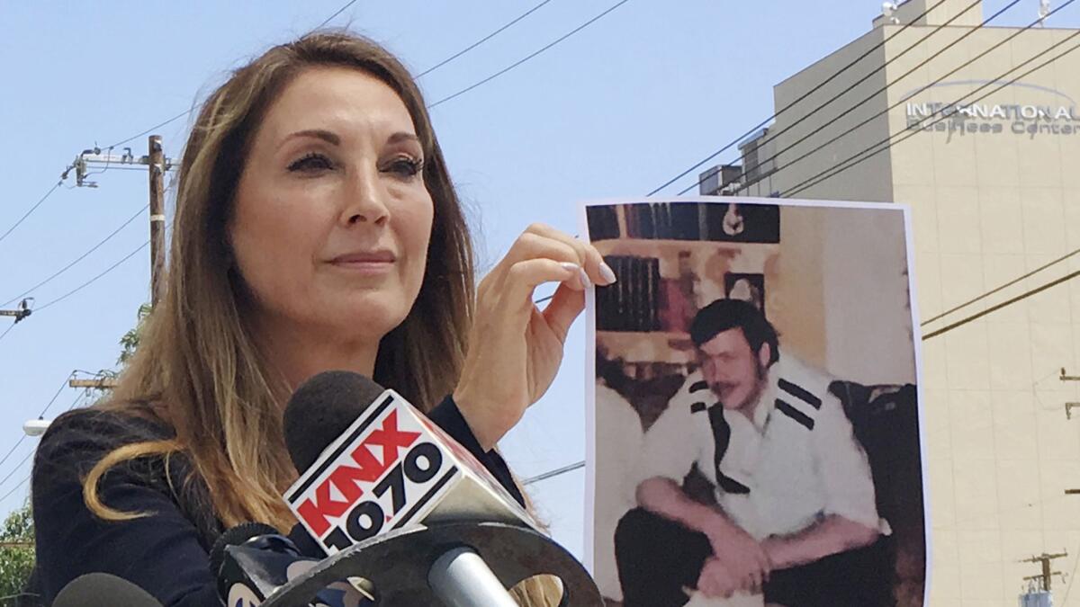 Attorney Annee Della Donna holds a photo of the late William Evins, who was convicted in the slaying of a woman in 1979, outside Superior Court in Santa Ana on Wednesday.