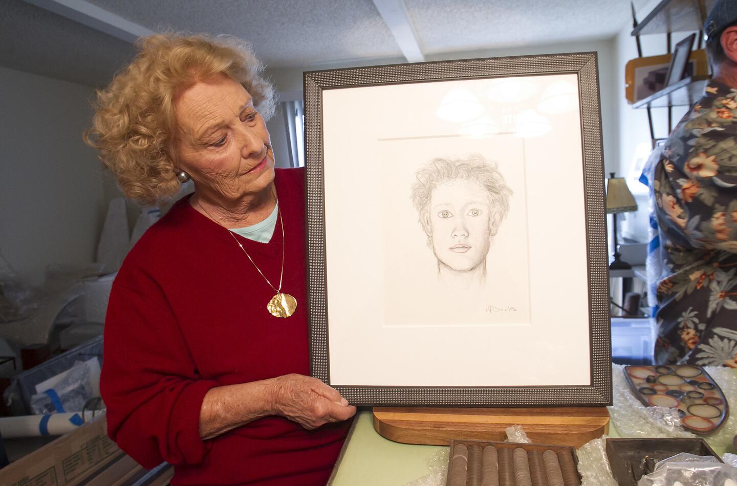 Carolyn McDemas holds a self-portrait of her late son James, who was a contemporary artist, designer, and sculptor who from Newport Beach. Her son had one of his sculptures installed at the Costa Mesa City Hall and will have it officially dedicated in ceremony in December.