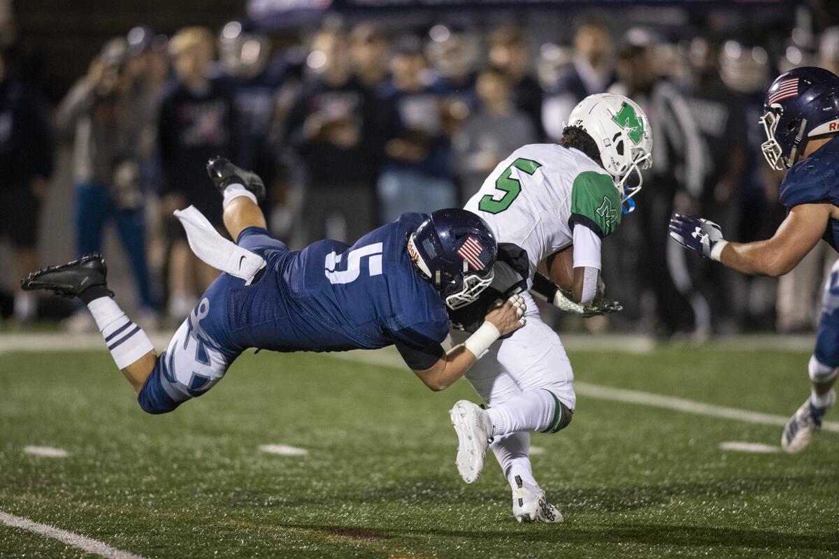 Newport Harbor's Johnny Brigandi goes for a ride while tackling Monrovia's Tyree Myles in the quarterfinals of the CIF Southern Section Division 9 playoffs on Friday.