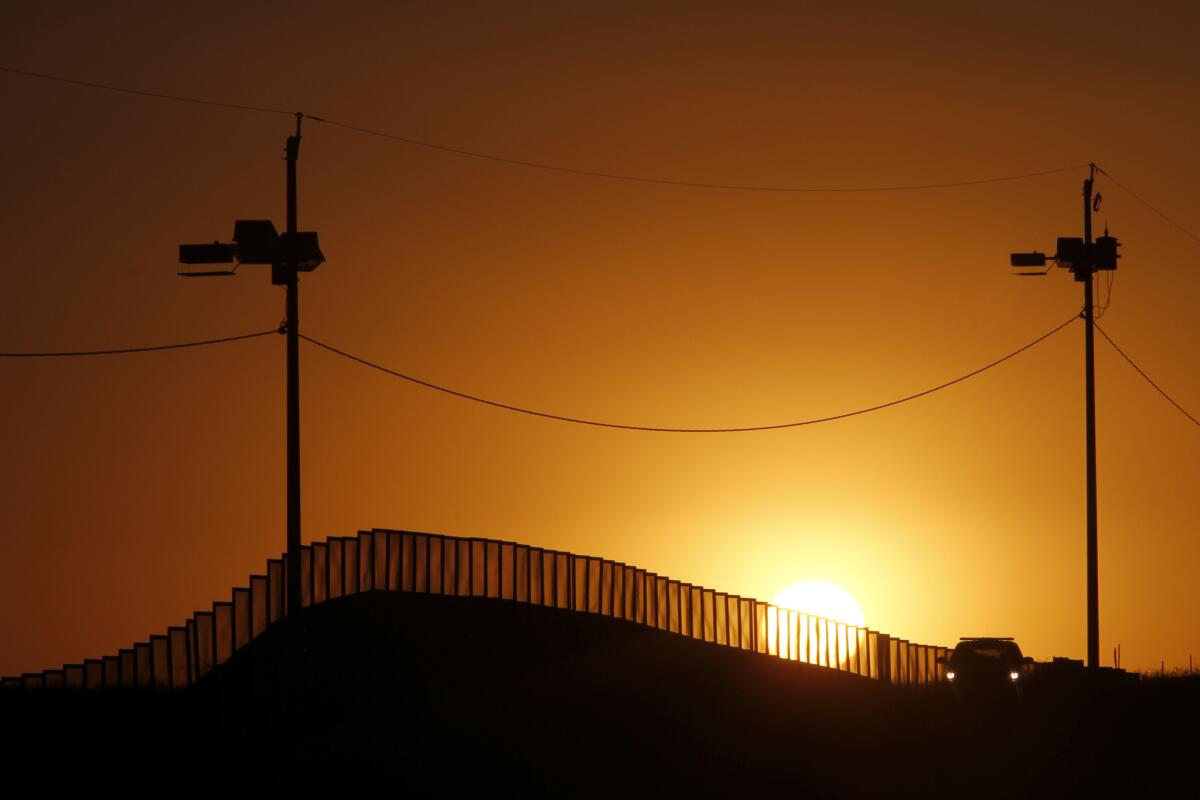 Sunset at the Mexico border in Naco, Ariz., with a Border Patrol vehicle close by.