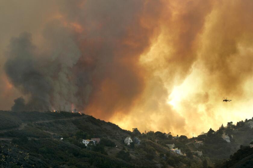 A helicopter flies toward a massive smoke plume rising from a wildfire in Malibu's Latigo Canyon in November.