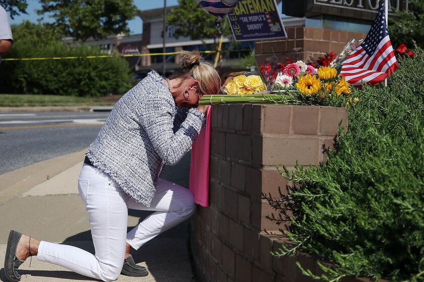 Lynne Griffin pays her respects at a makeshift memorial near the Capital newspaper offices, where five people were shot and killed Thursday in Annapolis, Md. Griffin was a journalism student under John McNamara, who was one of the people killed at the paper.