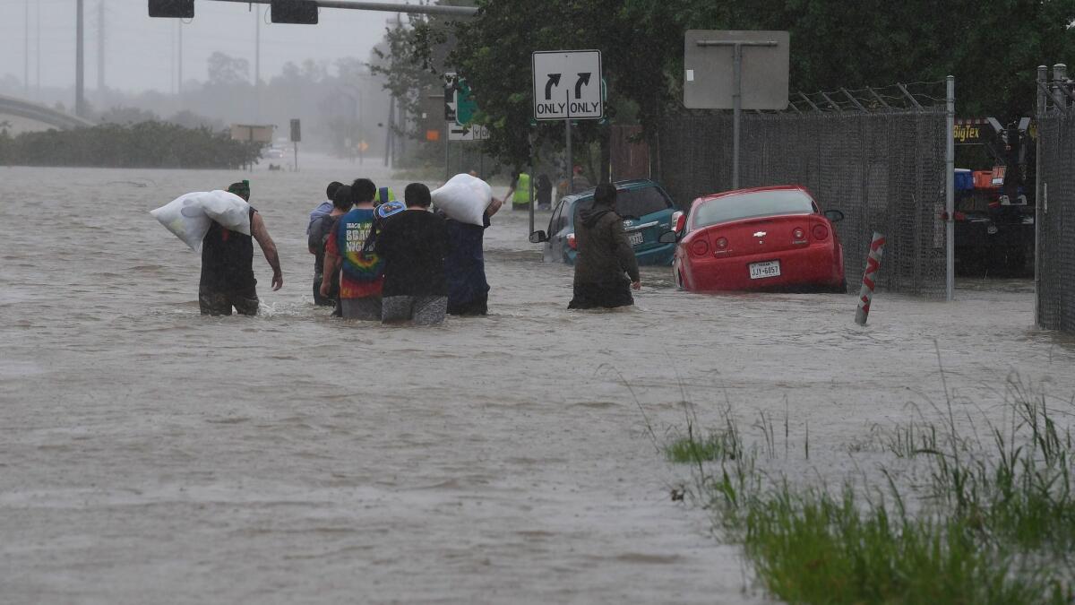 Evacuees wade through a flooded Highway 90 after fleeing their homes in Houston on Monday.