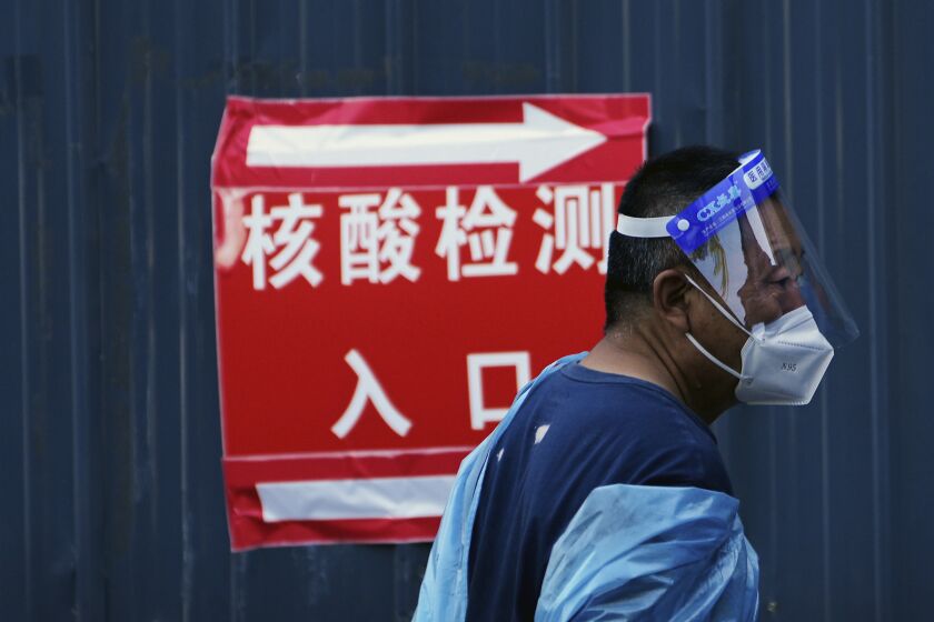 A volunteer wearing protective gears stands watch near a COVID-19 testing site in Beijing, Tuesday, Sept. 20, 2022. (AP Photo/Andy Wong)