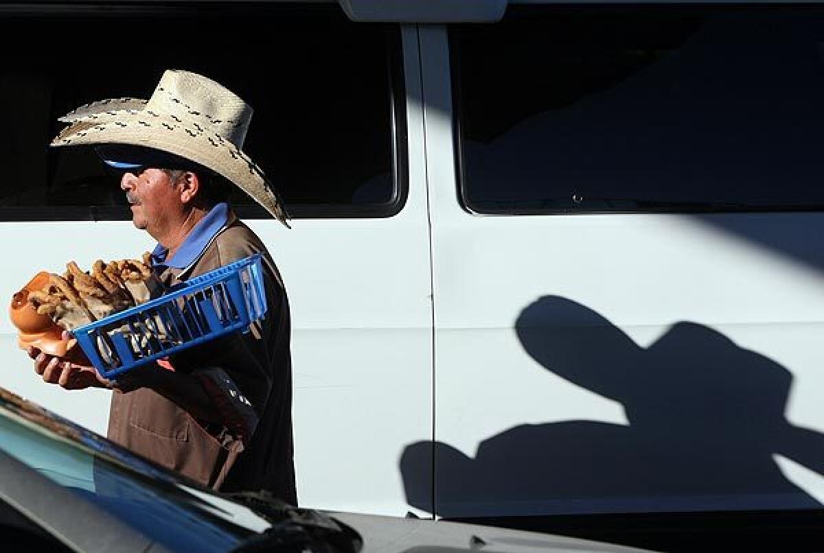 Deciderio Mauricio Cantera squeezes through lanes of idling cars inching toward the San Ysidro Port of Entry, wearing a stack of sombreros and holding a basket of churros.