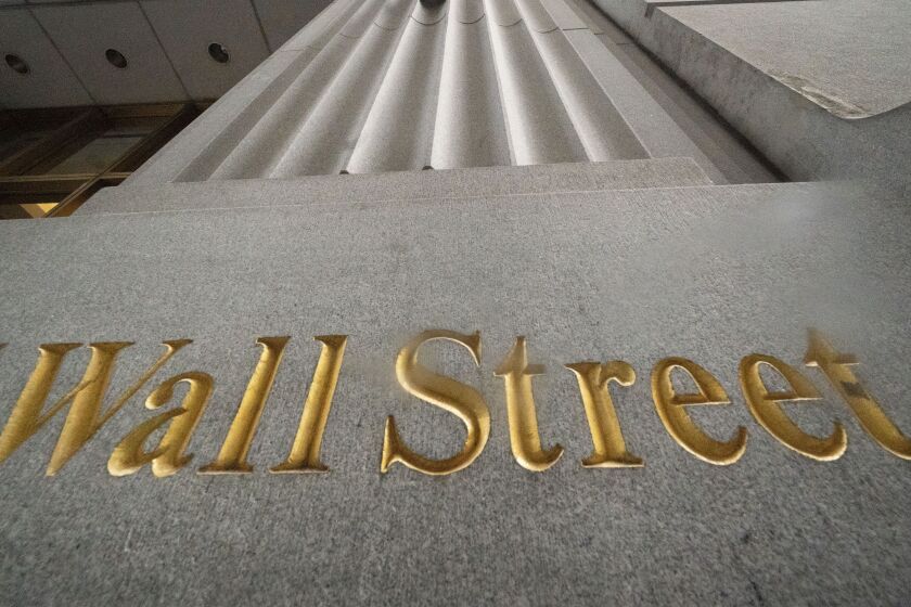 FILE - In this Nov. 5, 2020 file photo, a sign for Wall Street is carved in the side of a building, in New York. Stocks are opening mostly lower on Wall Street Wednesday, Aug. 4, 2021, led by declines in banks and energy companies. (AP Photo/Mark Lennihan, File)