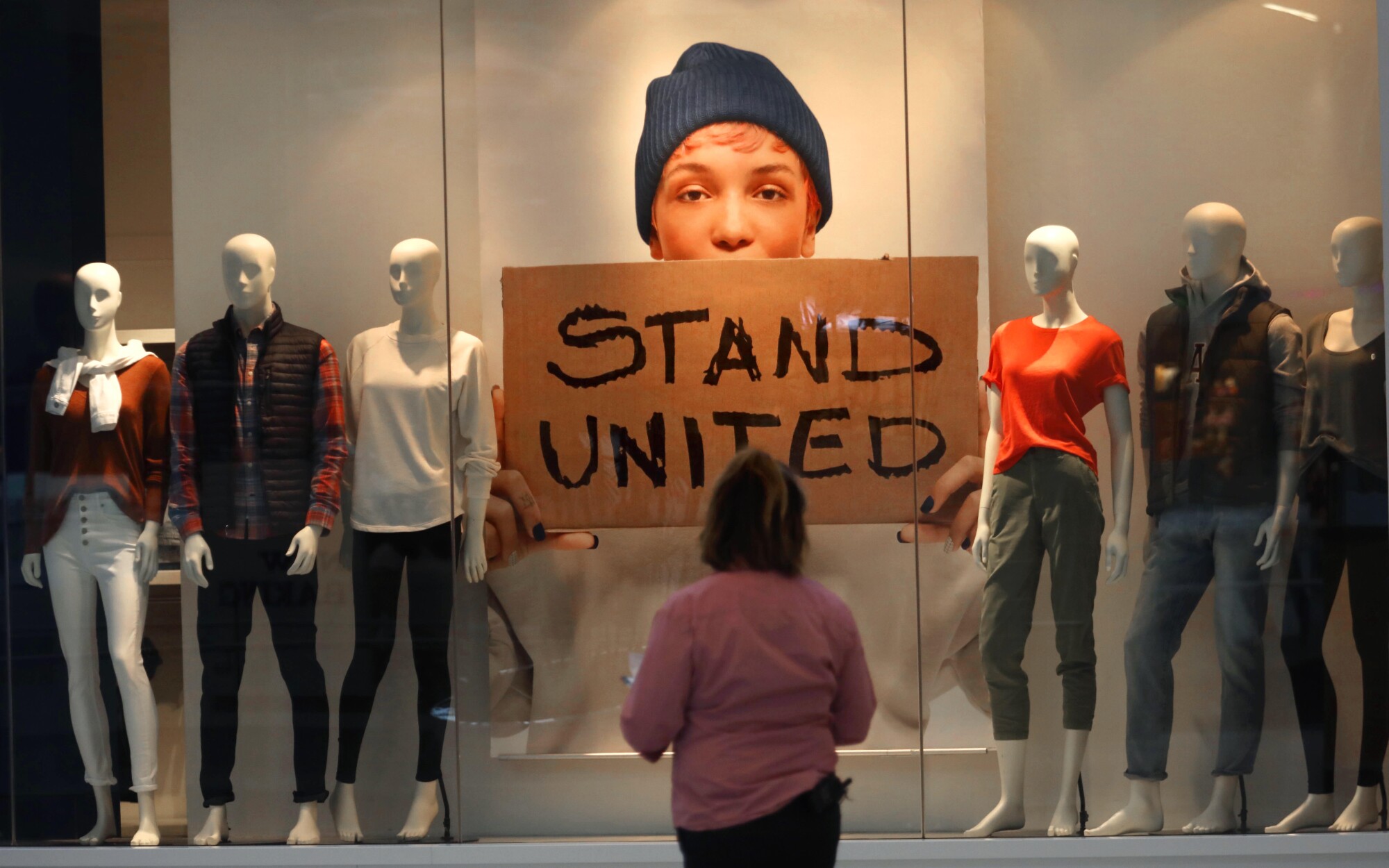 A woman looks at a window display including a sign saying "Stand United."