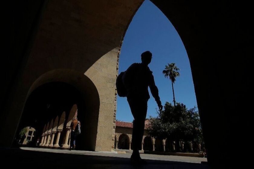 FILE - In this April 9, 2019, file photo, pedestrians walk on the campus at Stanford University in Stanford, Calif. Generally speaking, there are three types of award: free money, such as scholarships and grants; borrowed money, such as loans that need to be paid back; and earned money, such as work study in which you get a work-study job, earn the money and don’t have to repay it. The offer will vary from year to year. (AP Photo/Jeff Chiu, File)