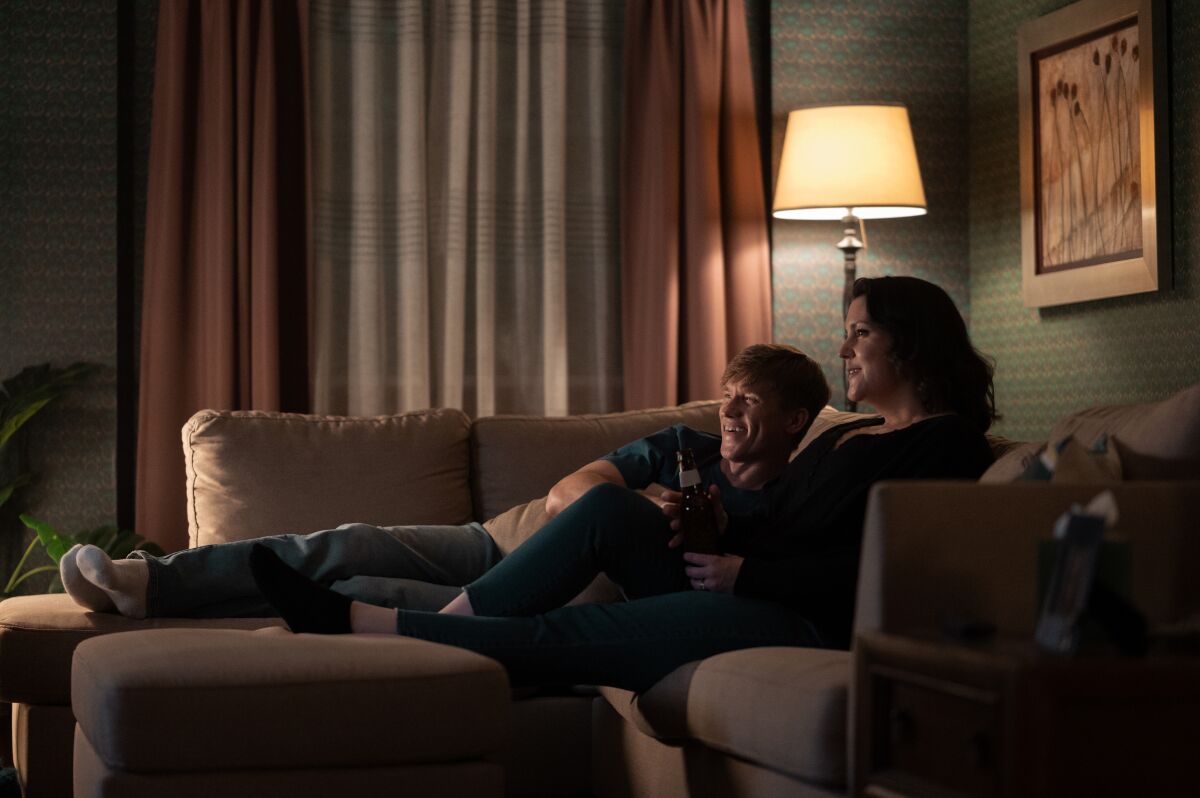 A husband and wife watching TV on the couch