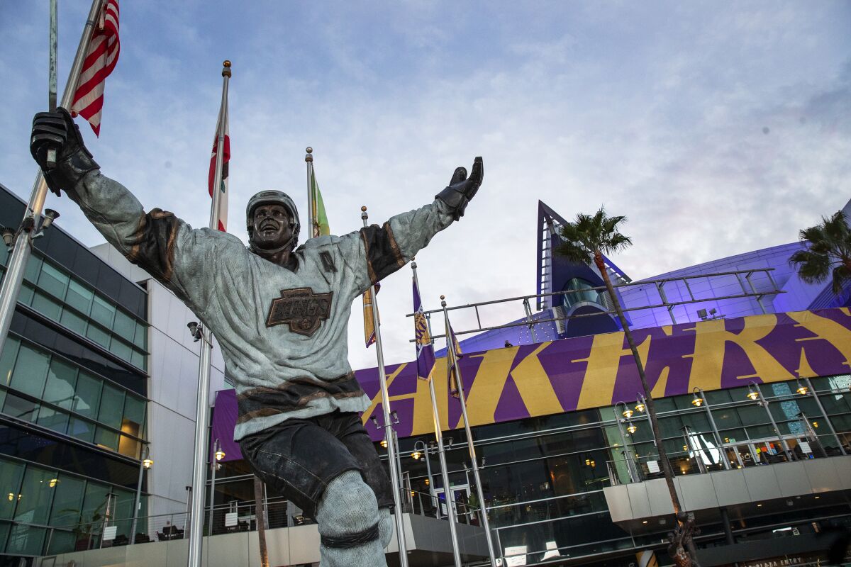 A statue of Luc Robitaille towers above metal framing where a Staples Center sign once hung