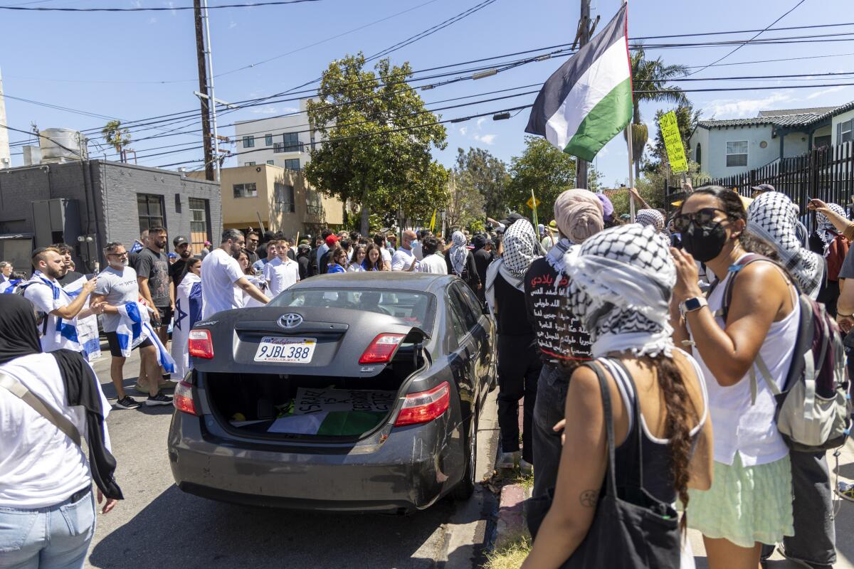 A pro-Palestinian protester gets into a car swarmed by pro-Israel protesters in Los Angeles.