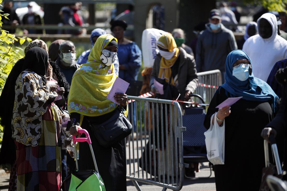 Residents arrive to collect soap, vegetables, fruits and other staples distributed by volunteers from community organizations in Clichy-sous-Bois, a suburb north of Paris.