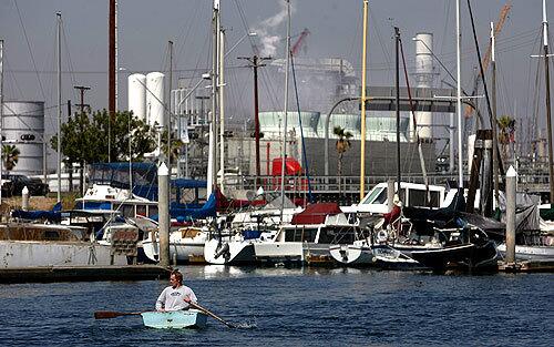 LIFE ON THE WATER: A Leeward Bay resident makes a short commute on his boat in the marina, which draws people looking for a low cost of living. About 75 residents live on boats floating in waters that are often a brew of debris, bacteria, pesticides and other toxic substances flowing from inland cities.