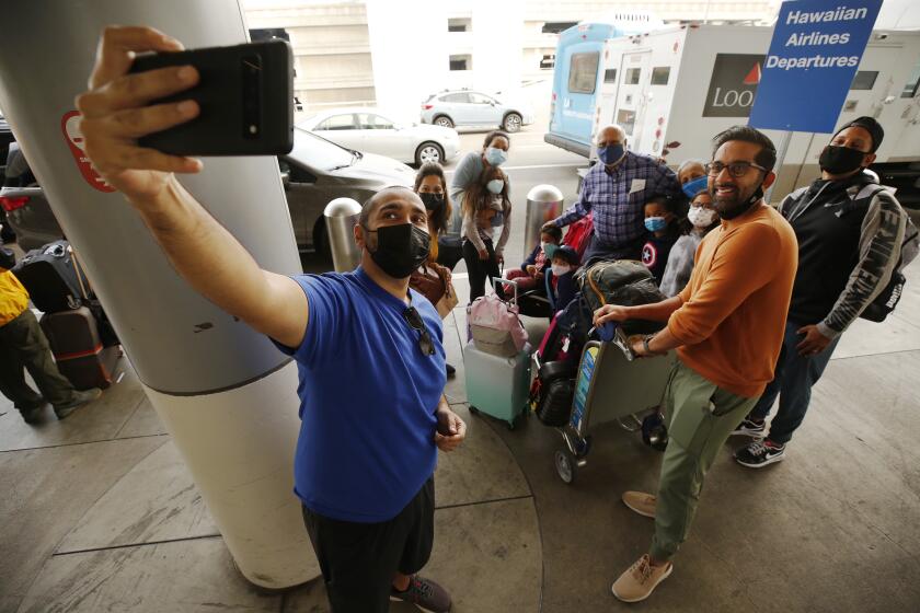 LOS ANGELES, CA - NOVEMBER 18: Abid Kapadya takes a selfie with the Kapadya family as they prepare to travel to Iraq for a religious trip over the Thanksgiving holiday. A few travelers at Los Angeles International Airport LAX are beating the crowds on Thursday as up to 2 million people are expected to pass through Los Angeles International Airport during the two-week Thanksgiving holiday period that begins today, potentially doubling the number from the same time last year. The busiest days are expected to be this Friday and the Sunday after Thanksgiving, November 28th. LAX on Thursday, Nov. 18, 2021 in Los Angeles, CA. (Al Seib / Los Angeles Times).