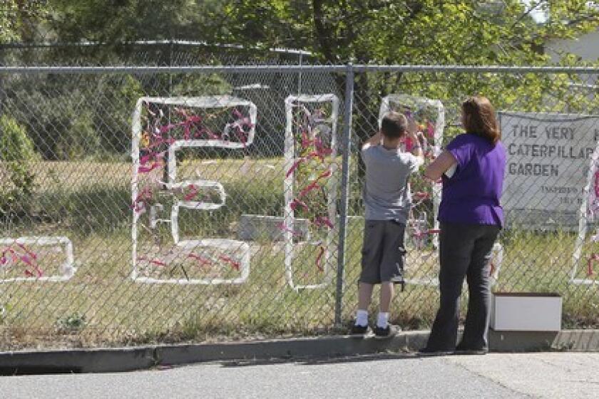 Teacher Cecilia Richardson helps a student tie a ribbon honoring murder victim, A student ties a ribbon to a fence honoring Leila Fowler at Jenny Lind Elementary School in Valley Springs, Calif., after the third-grader was stabbed to death at her home.