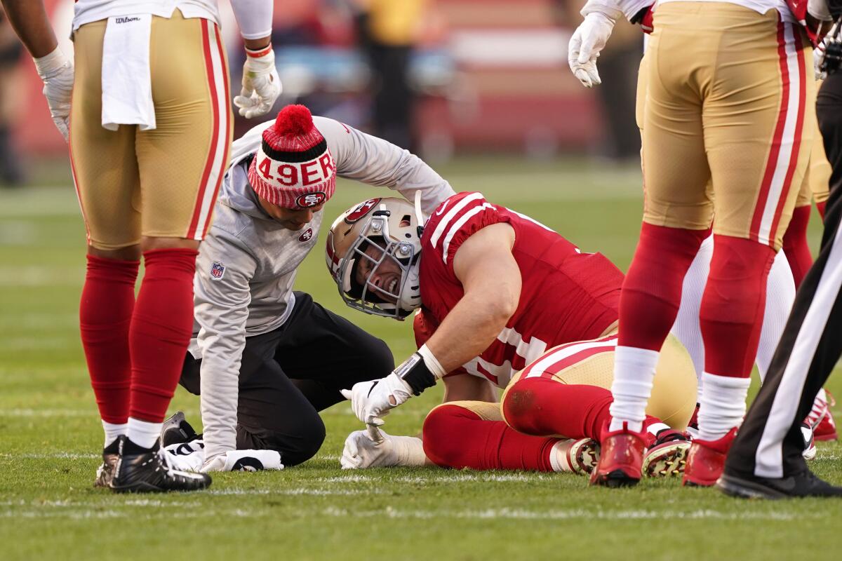 A trainer checks on San Francisco rookie Nick Bosa during the 49ers' playoff game against the Minnesota Vikings on Saturday.