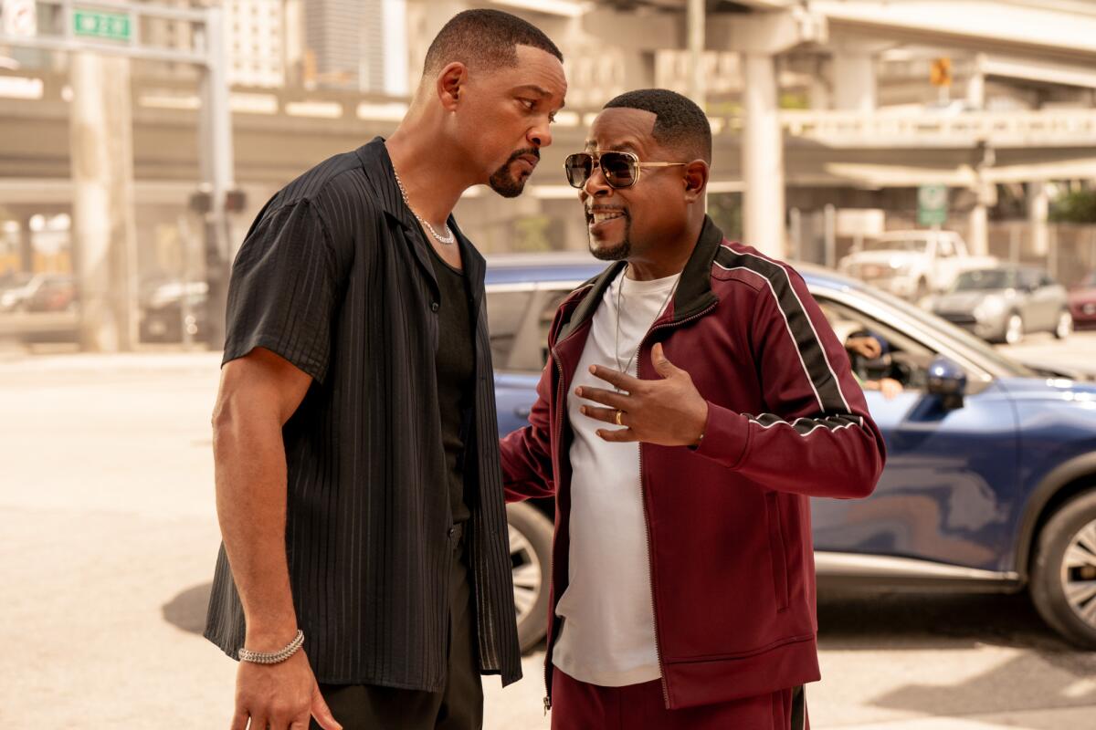 Will Smith leans in to listen as Martin Lawrence speaks and gestures with a hand in a scene from "Bad Boys: Ride or Die."