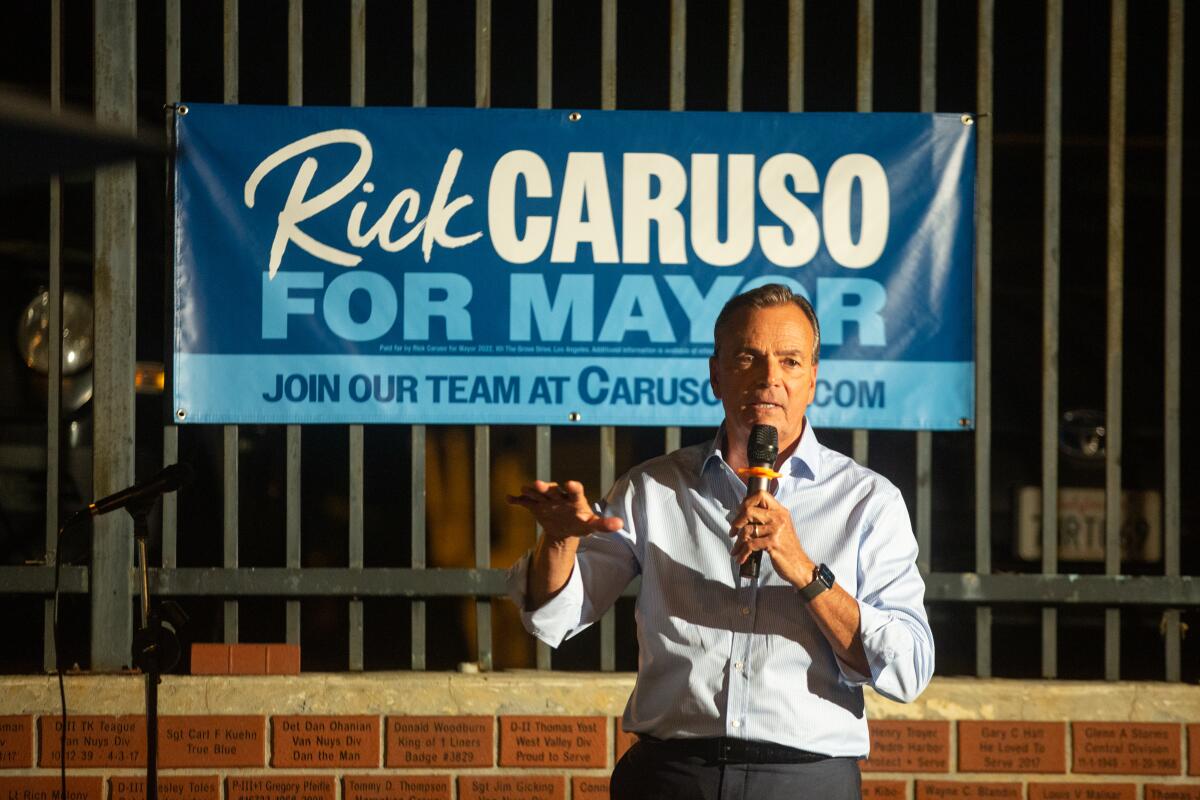 Rick Caruso in front of a Rick Caruso for mayor sign