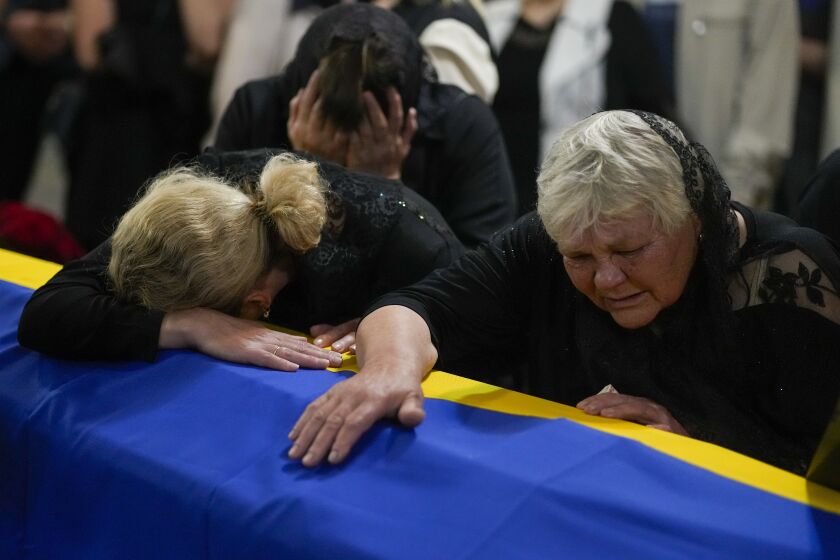 The mother, right, and sister of Army Col. Oleksander Makhachek mourn over the coffin with his remains during a funeral service in Zhytomyr, Ukraine, Friday, June 3, 2022. According to combat comrades Makhachek was killed fighting Russian forces when a shell landed in his position on May 30. (AP Photo/Natacha Pisarenko)