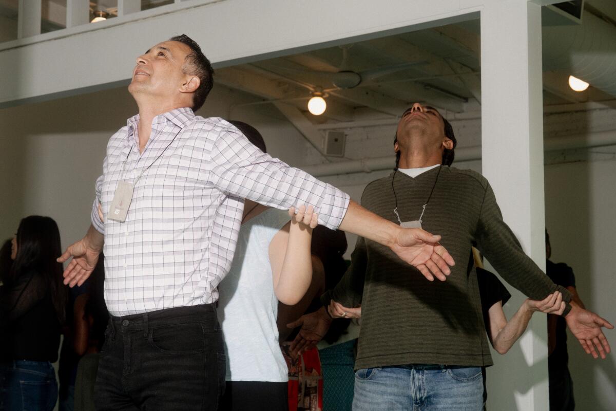 Two men hold their heads up while stretching their arms out 