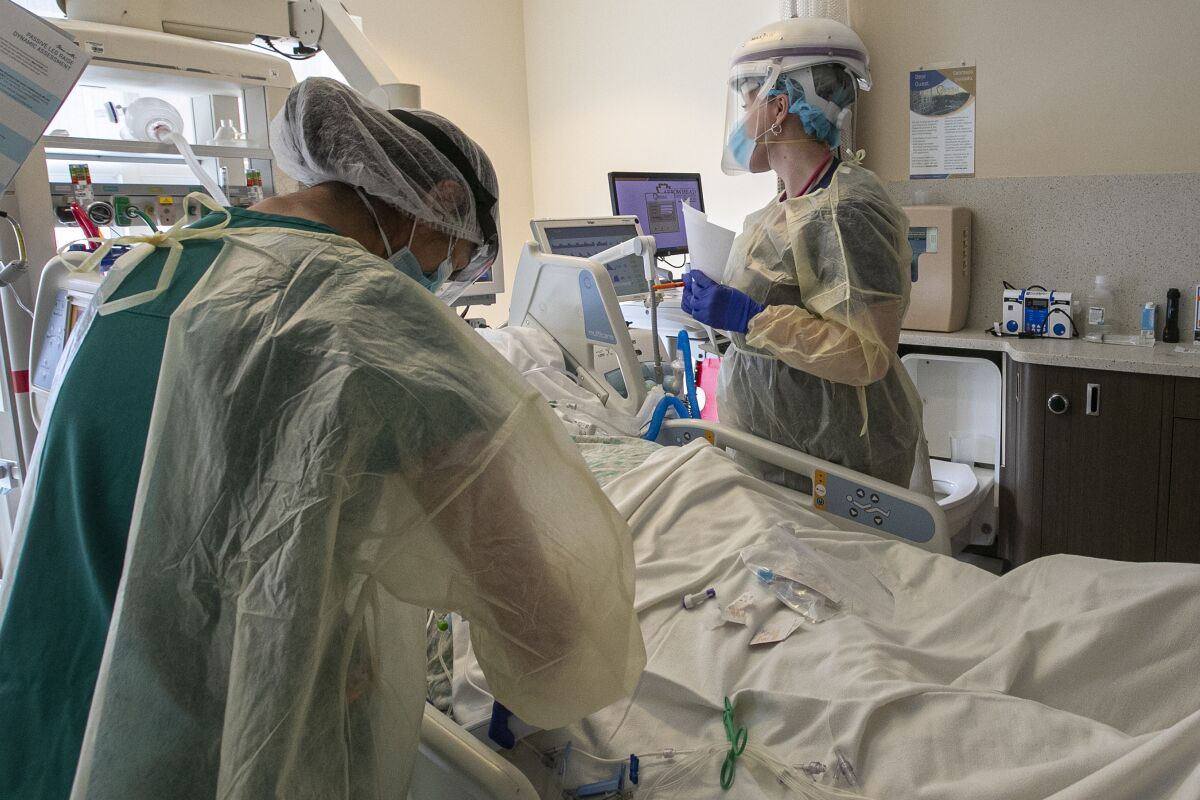 A nurse and respiratory therapist attend to a COVID-19 patient.