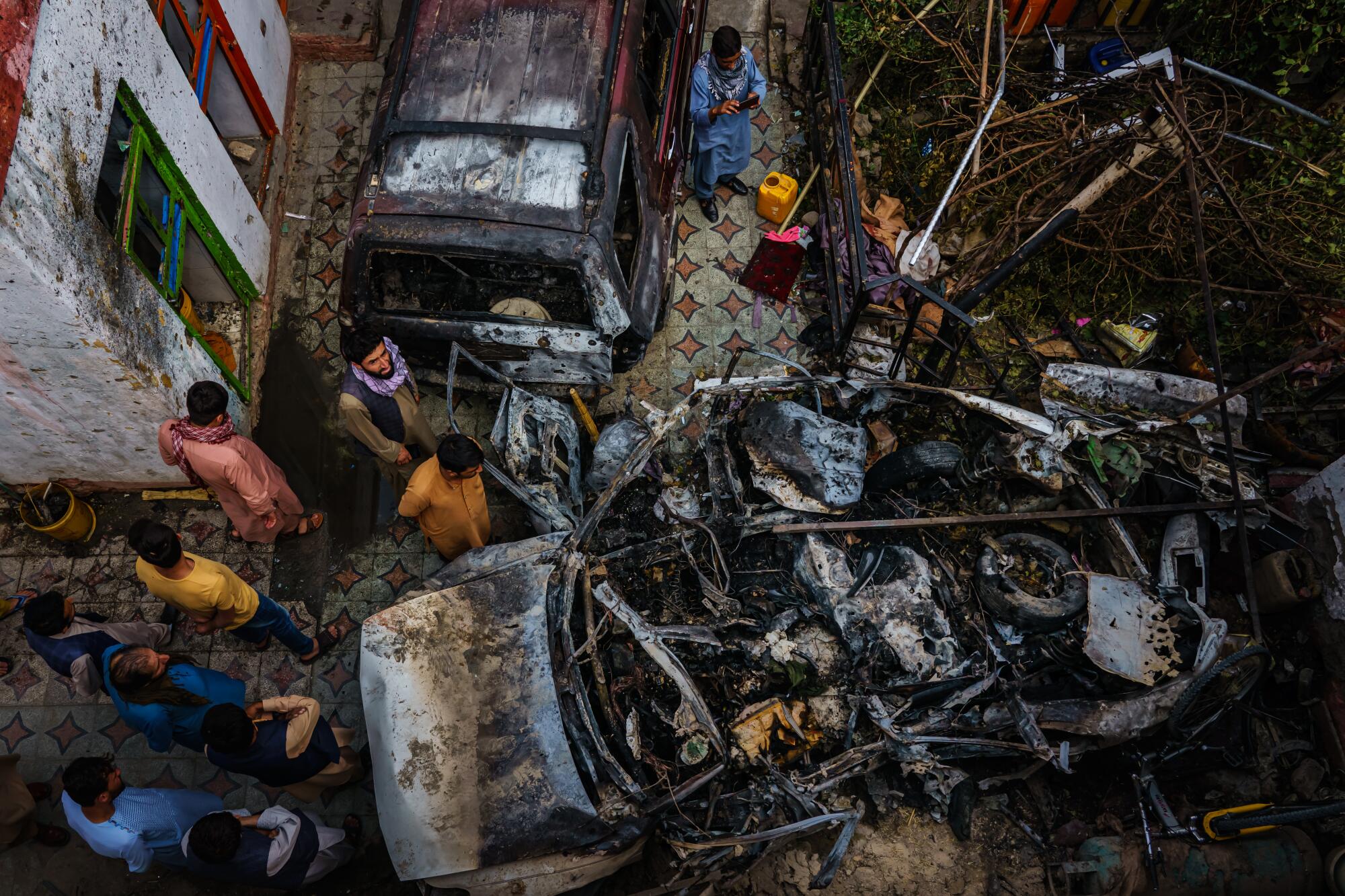 People gathering around burned-out vehicle