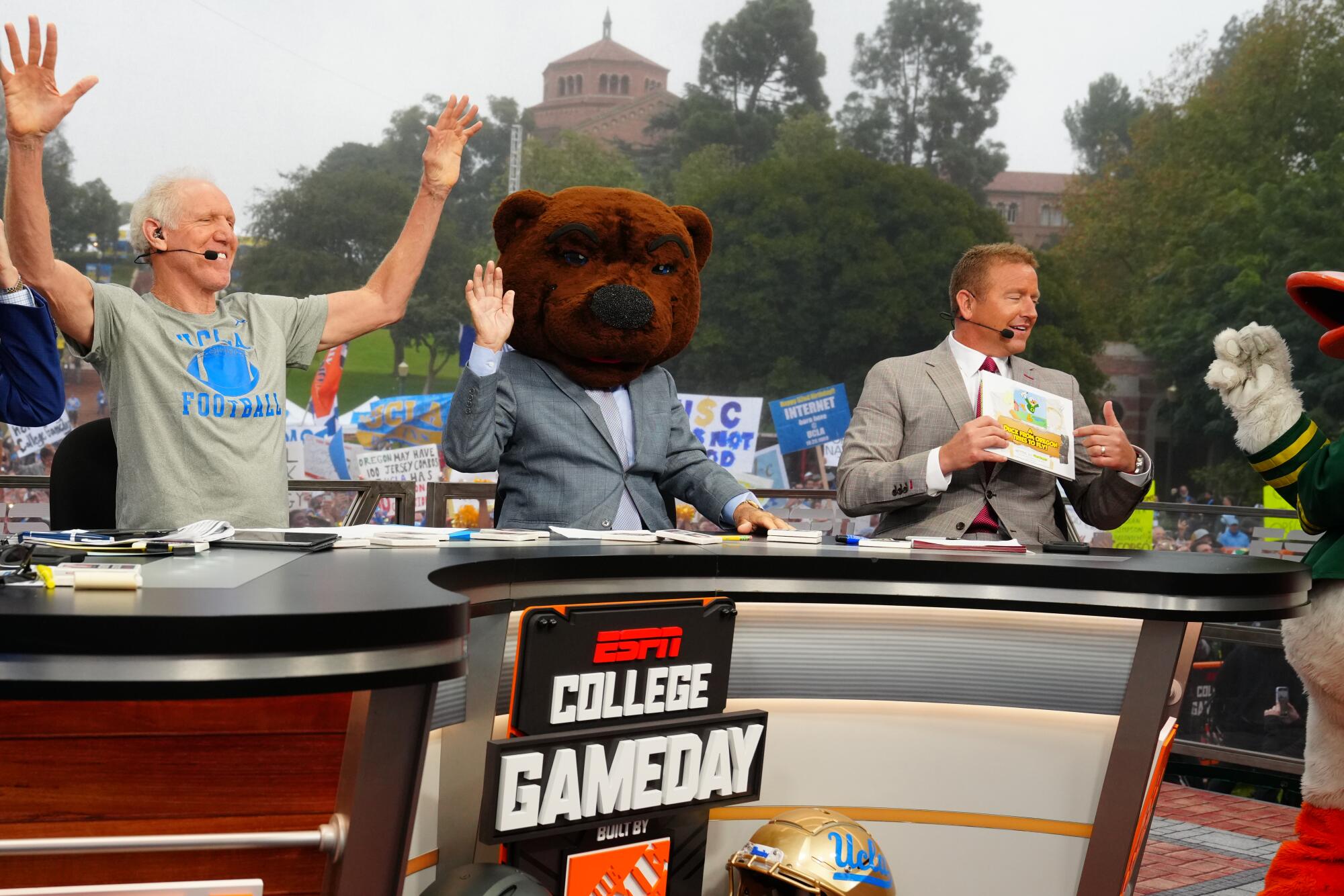 Celebrity picker Bill Walton, left, reacts as Lee Corso puts on a bear head to indicate he's picking UCLA to beat Oregon 