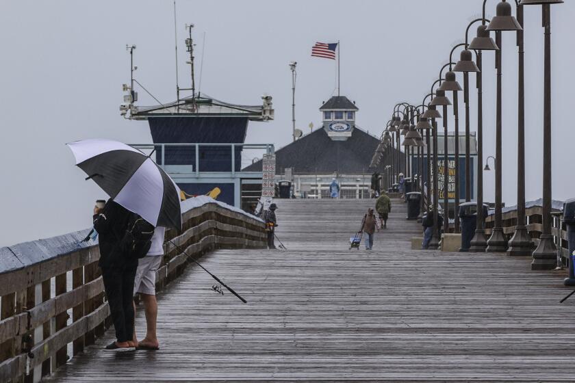 Imperial Beach, CA - September 09: Despite high wind and rain, people enjoy the stormy weather during the morning hours on the Imperial Beach Pier on Friday, Sept. 9, 2022 in Imperial Beach, CA. (Eduardo Contreras / The San Diego Union-Tribune)