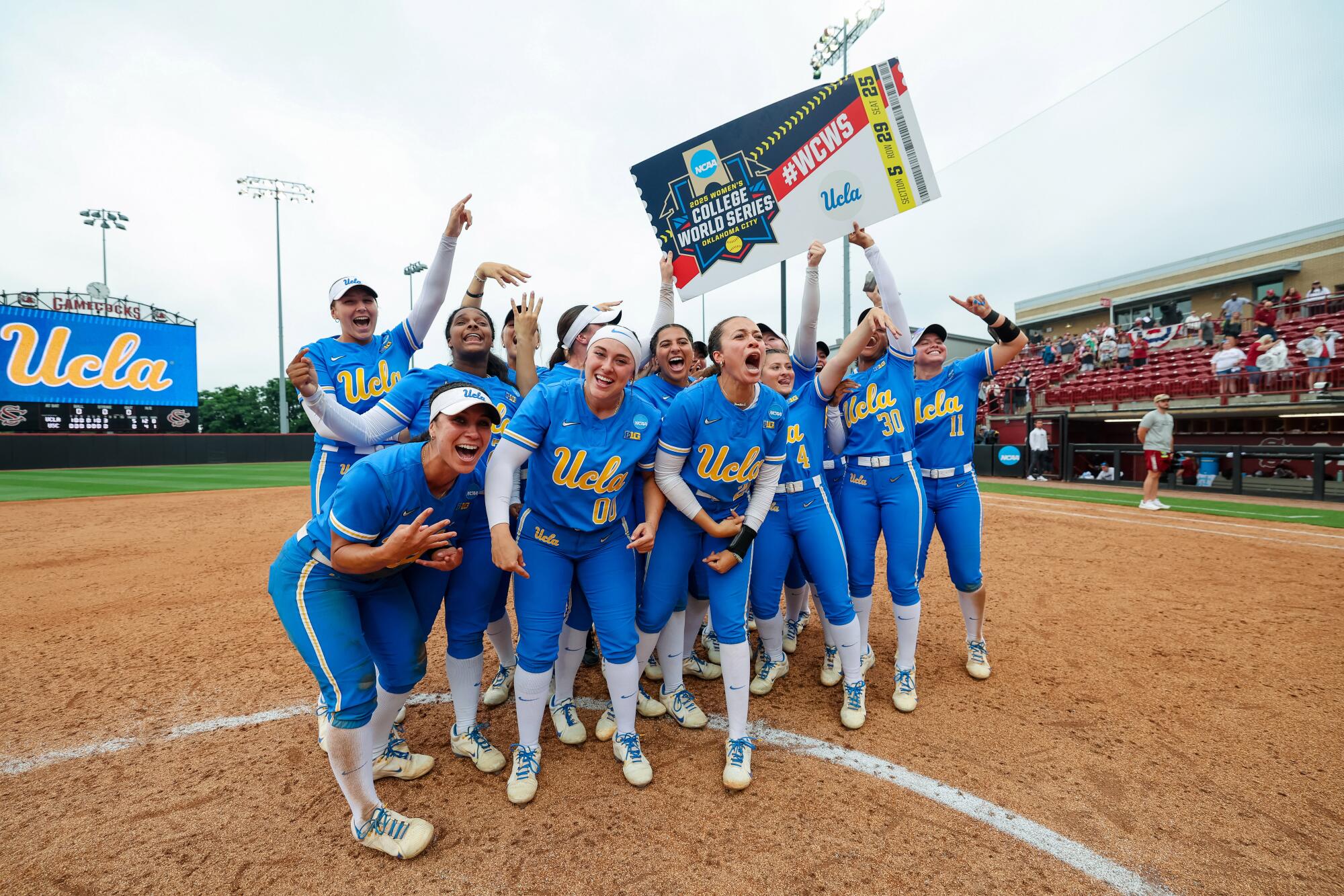 UCLA players celebrate with an oversized ticket to the Women's College World Series after beating South Carolina Sunday.