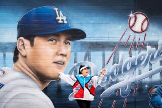 HERMOSA BEACH-CA-DECEMBER 19, 2023: Kumi Suio, a Japanese tour guide from Gardena, dances in front of a mural featuring newest Dodger player Shohei Ohtani by artist Gustavo Zermeno, Jr. on the side wall of Ocean View Liquor store in Hermosa Beach on Tuesday, December 19, 2023. (Christina House / Los Angeles Times)