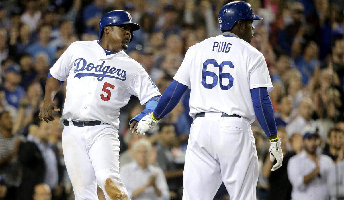 Dodgers third baseman Juan Uribe (5) is greeted by center fielder Yasiel Puig after scoring on a sacrifice fly by Dee Gordon in the fifth inning against the Giants on Monday night.
