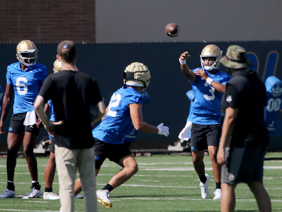 UCLA quarterback Dante Moore warms up by passing the ball during practice