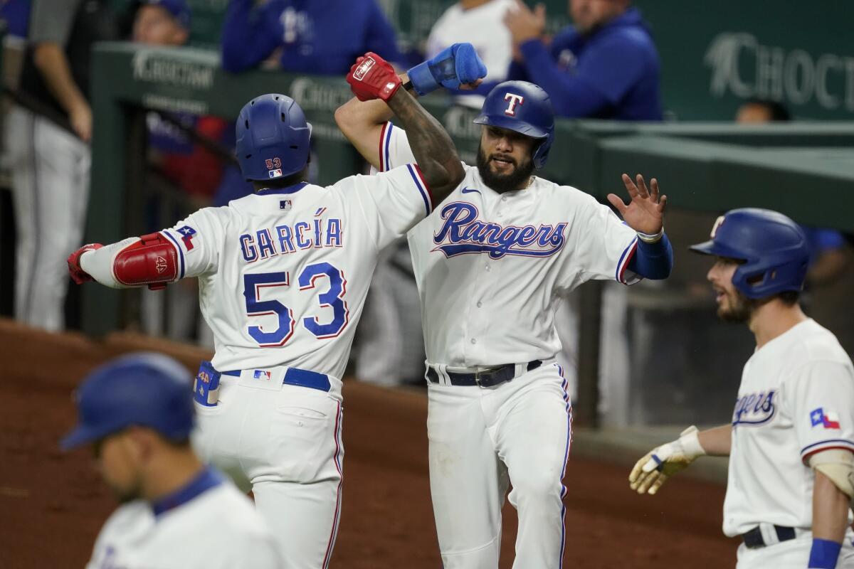 Texas Rangers' Adolis Garcia (53) and Isiah Kiner-Falefa, center right, celebrate Garcia's two-run home run that scored Kiner-Falefa against the Houston Astros during the the third inning of a baseball game in Arlington, Texas, Tuesday, Sept. 14, 2021. In the foreground are Rangers' Nathaniel Lowe, left, and Nick Solak. (AP Photo/Tony Gutierrez)