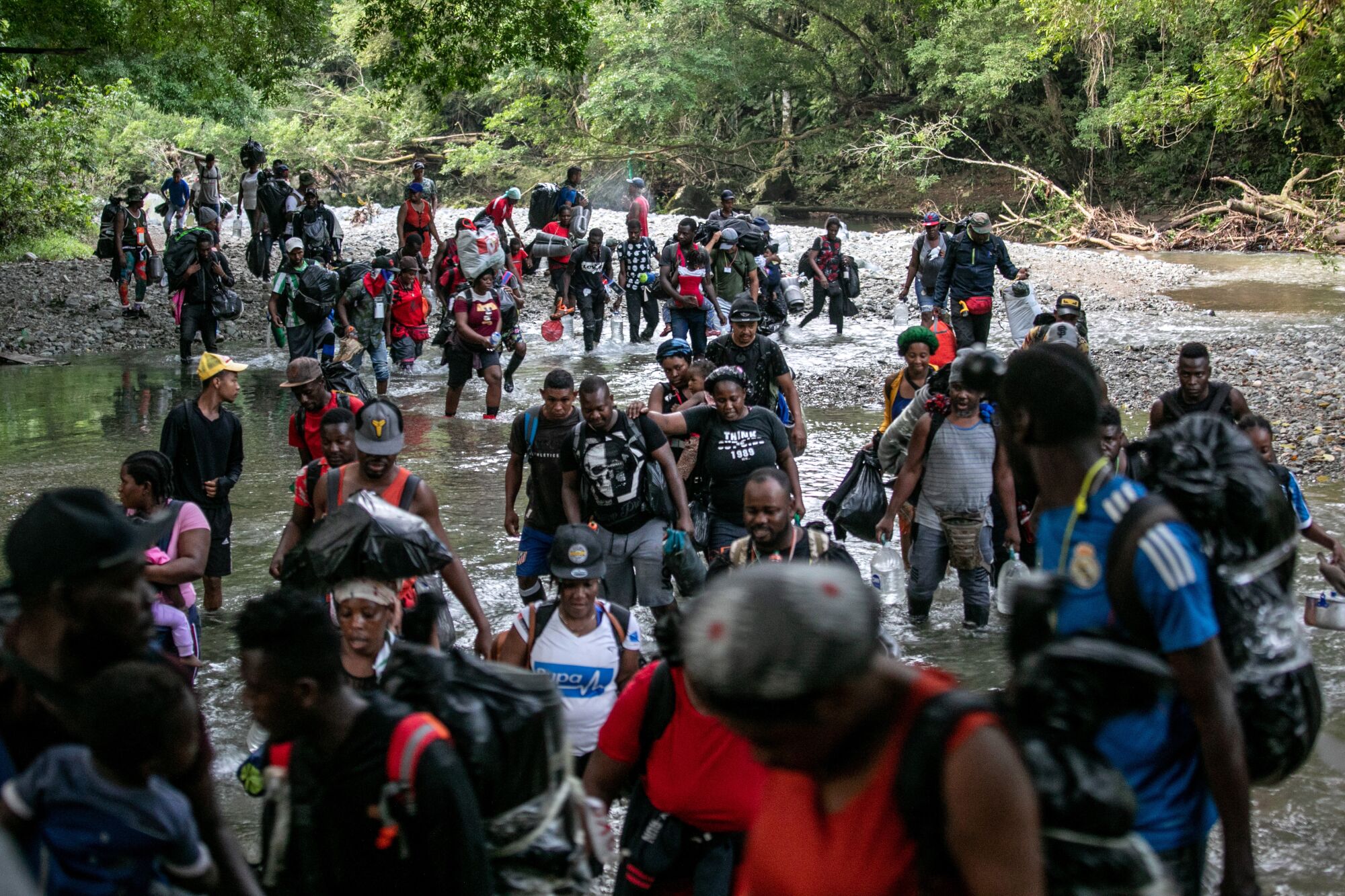 Migrants, most from Haiti, ford one of many rivers they will cross while on a trek through the infamous Darien Gap.