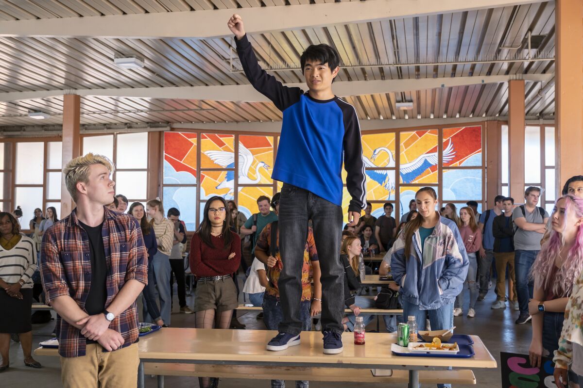 Ben Wang standing with his fist raised on a lunch table