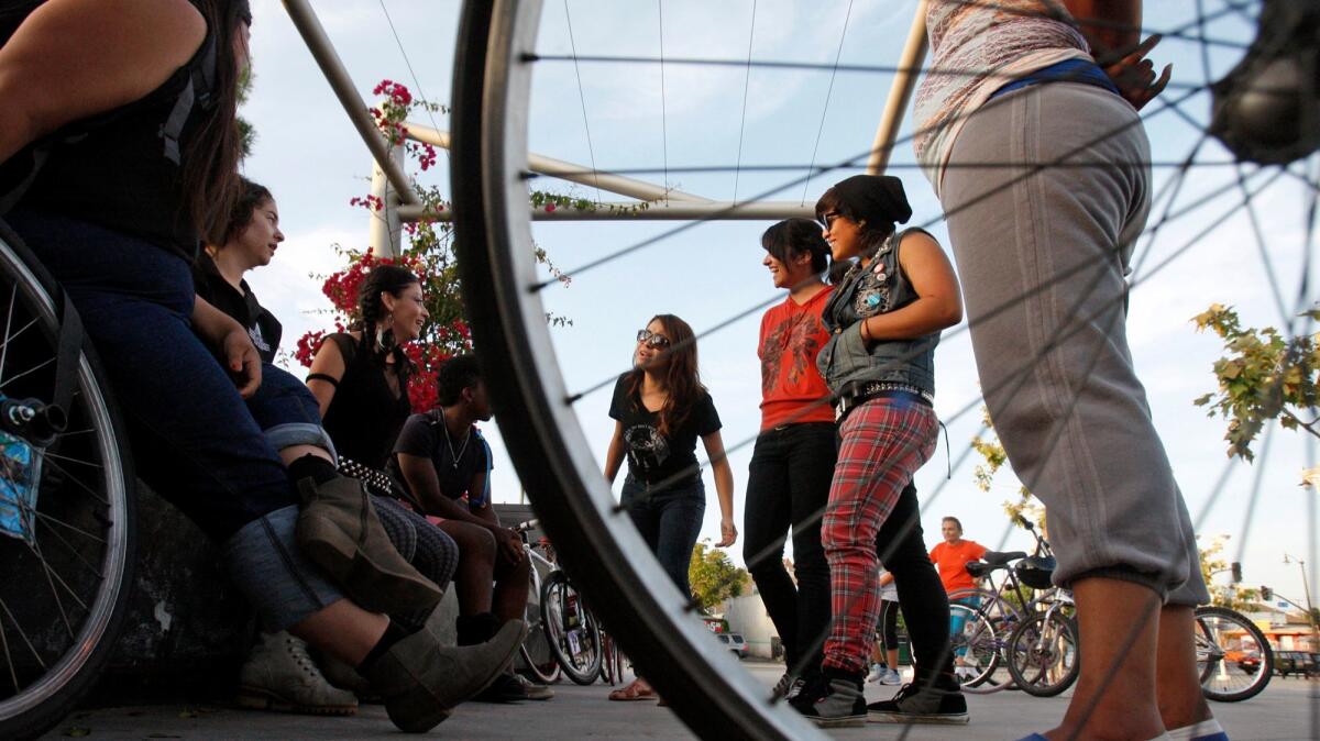 Female bike riders, along with a few members of the Ovarian Psycos, talk with one another before their evening ride through the Boyle Heights area of Los Angeles in June 2013. (Gary Friedman / Los Angeles Times)